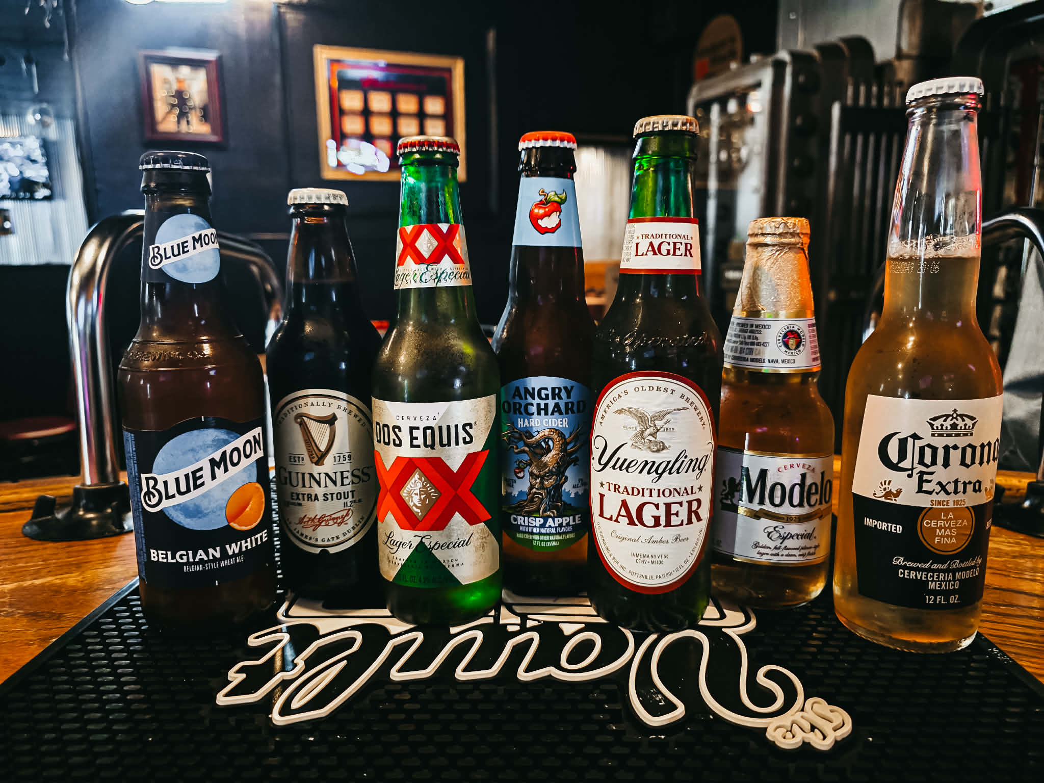 Import beer bottle lineup at The Vault — Blue Moon, Guinness, Dos Equis, Modelo, Corona